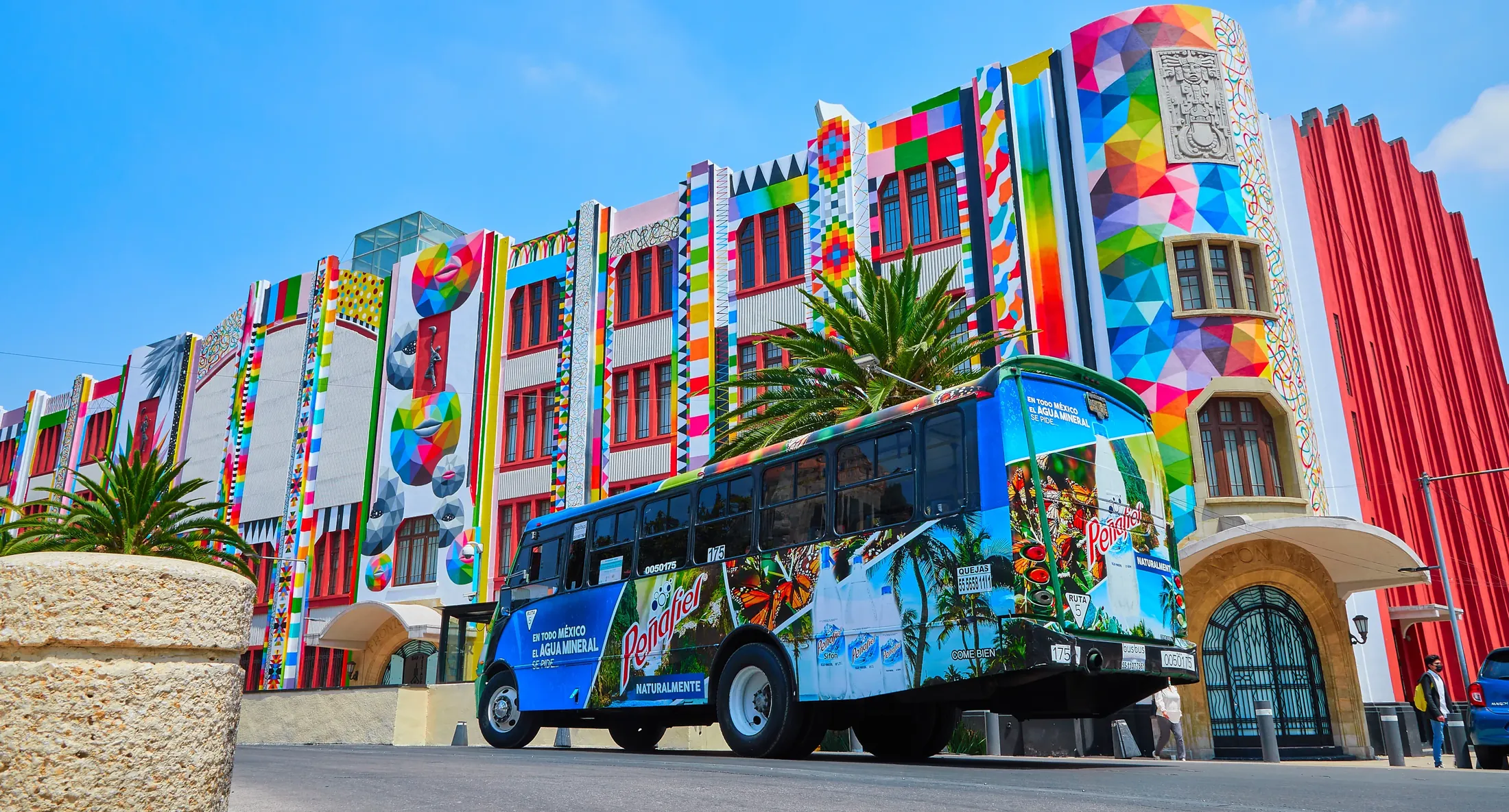 Autobús urbano Peñafiel con publicidad publicitaria BusBus frente a edificio colorido